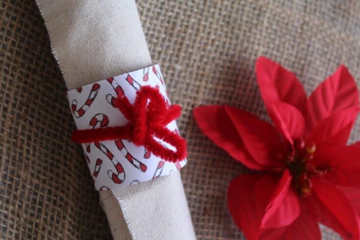 Picture of a rolled up napkin wrapped with a simple piece of toilet paper tube covered in candy cane paper and tied with a red pipe cleaner