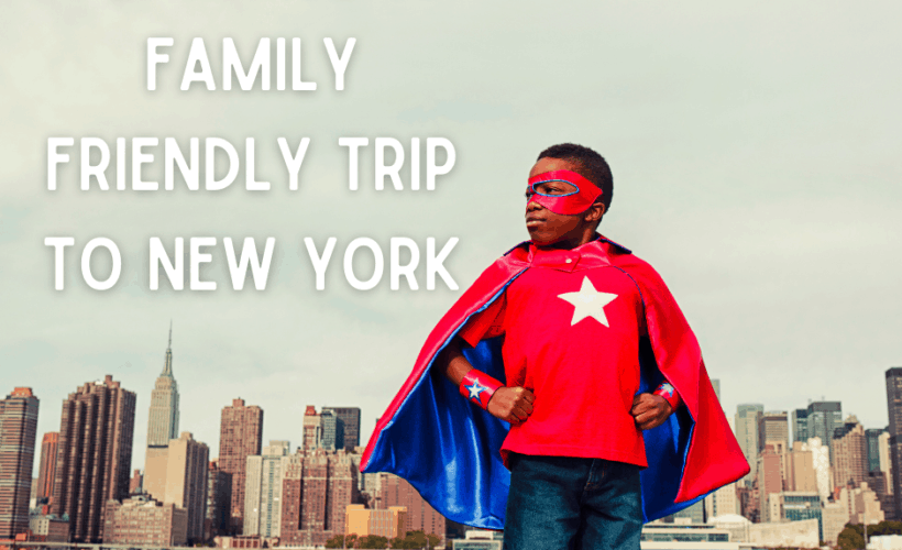 boy in superhero cape and mask standing across river from new york city