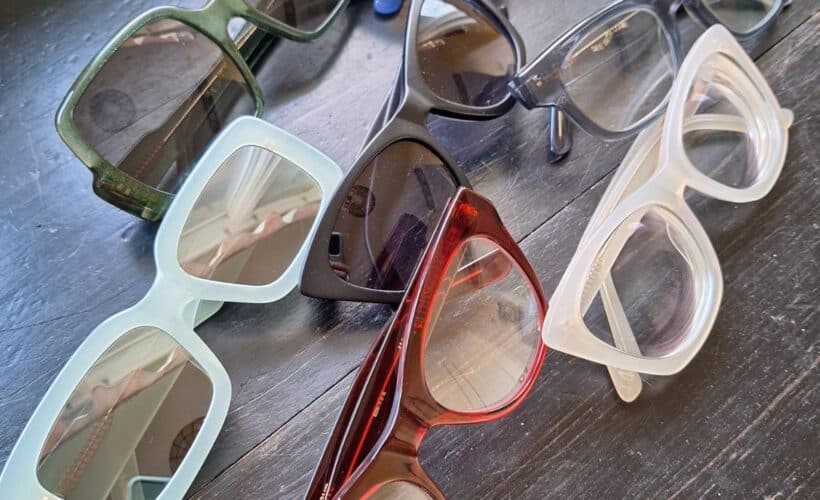 Several pairs of DL Eyewear glasses and sunglasses on a table