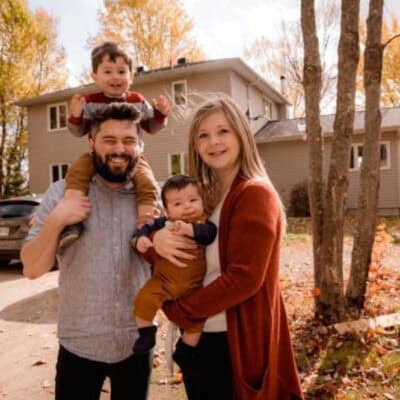 Parents holding their children in their front yard.