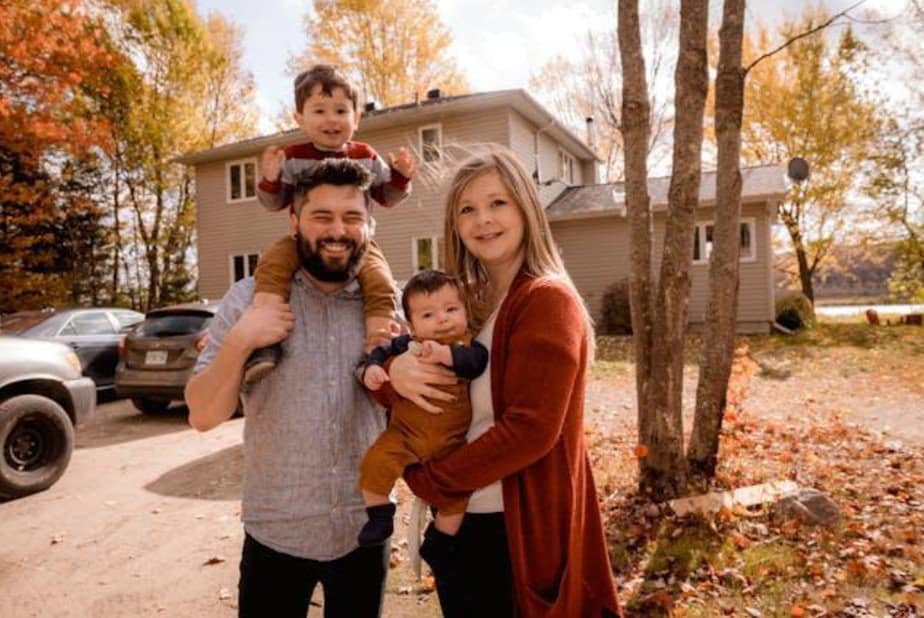 Parents holding their children in their front yard.